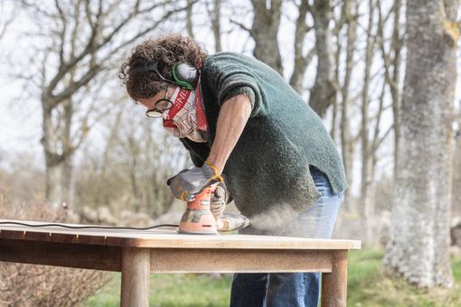 Furniture repair technician sanding a wooden table